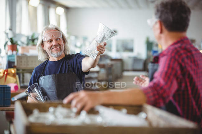 Ventilateur montrant vase en verre à un collègue à l'usine de soufflage de verre — Photo de stock