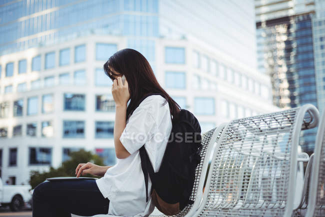 Mulher falando no celular enquanto usa tablet digital — Fotografia de Stock
