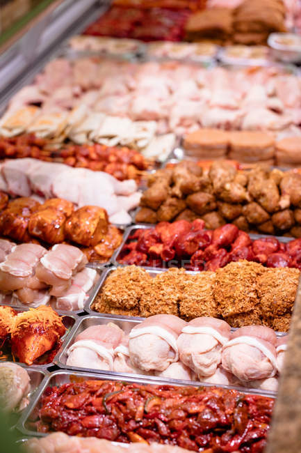 Variety of marinated meat at display counter in butchers shop — Stock Photo