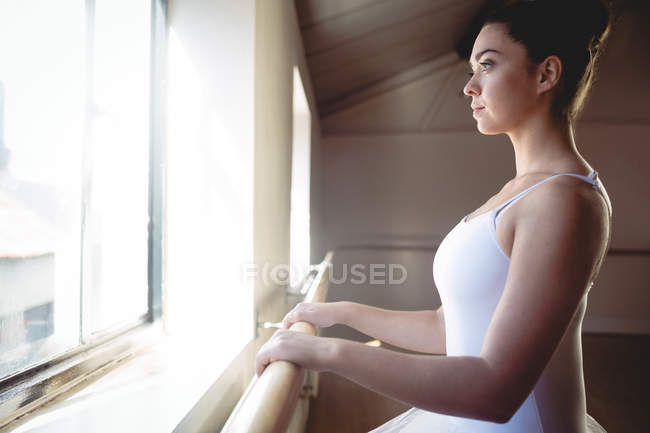Side view of Ballerina holding bar in studio and looking away — Stock Photo