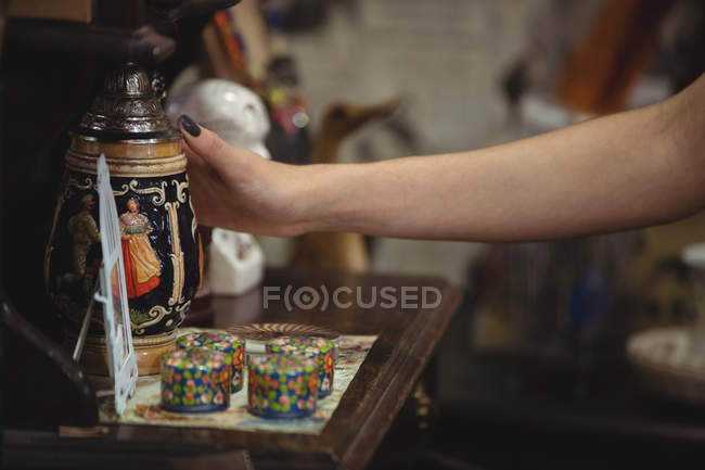 Mano de mujer sosteniendo frasco antiguo en tienda de antigüedades - foto de stock