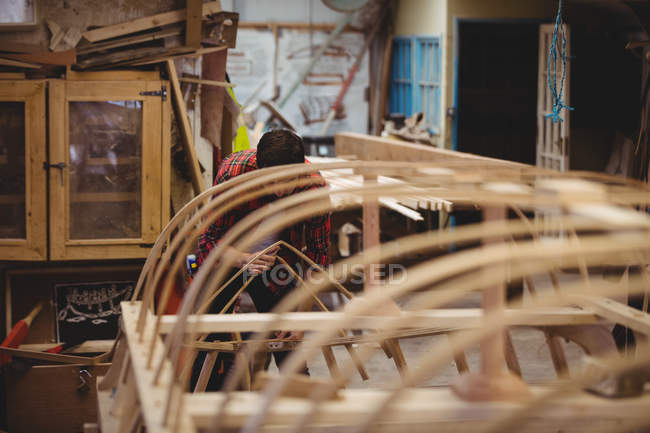 Homem preparando uma moldura de barco de madeira no estaleiro — Fotografia de Stock
