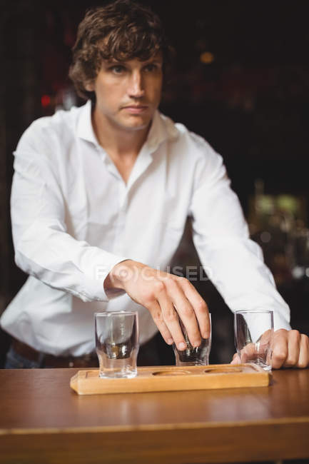 Barman organizando copo de cerveja na bandeja no balcão do bar no bar — Fotografia de Stock