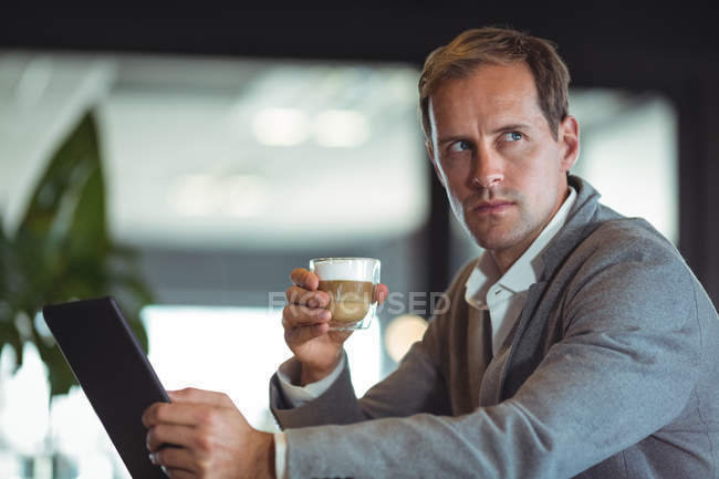 Бізнесмен, використовуючи мобільний телефон, маючи каву в кафе — стокове фото