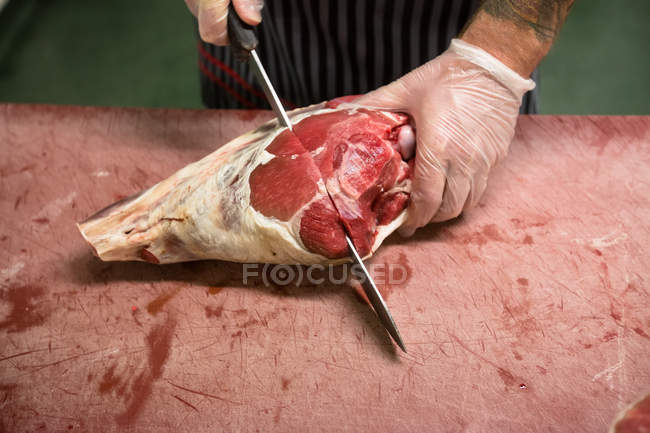 Mains de boucher coupant la carcasse de porc avec un couteau dans la boucherie — Photo de stock