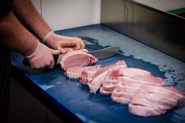 Mãos de açougueiro cortando carne no açougue — Fotografia de Stock