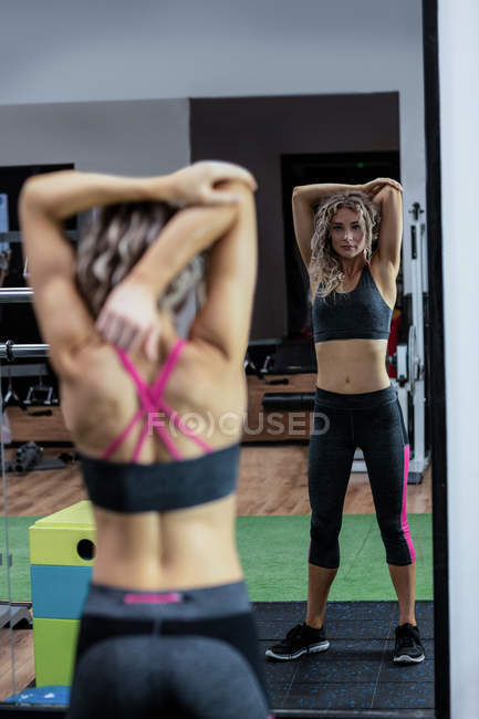 Beautiful woman performing stretching exercise in gym — Stock Photo