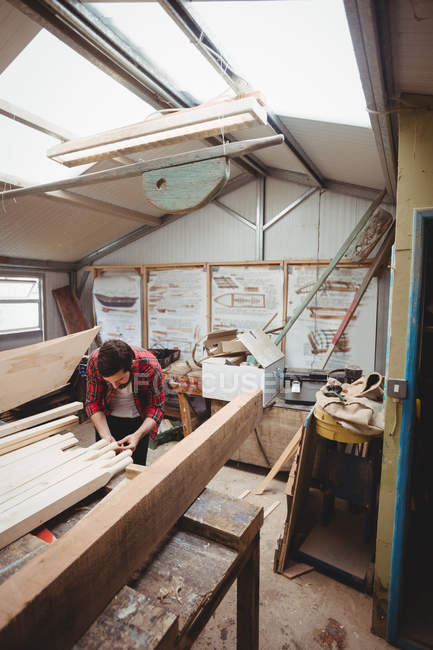 Man working on wooden plank in boatyard — Stock Photo