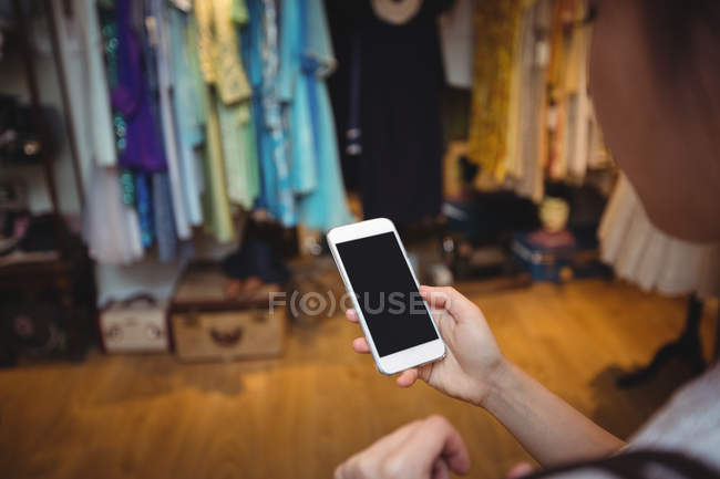 Hand of woman using mobile phone in apparel store — Stock Photo
