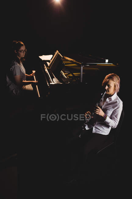 Две студентки играют на кларнете и фортепиано в студии — стоковое фото