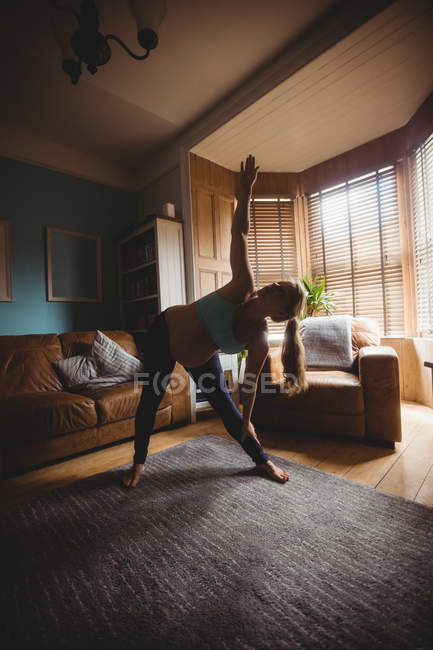 Спортивная беременная женщина выполняет упражнения на растяжку в гостиной на дому — стоковое фото