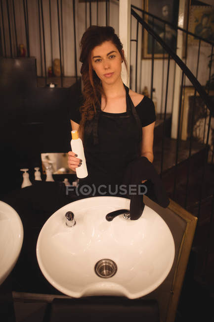 Female hairdresser holding bottle of a shampoo at saloon — Stock Photo