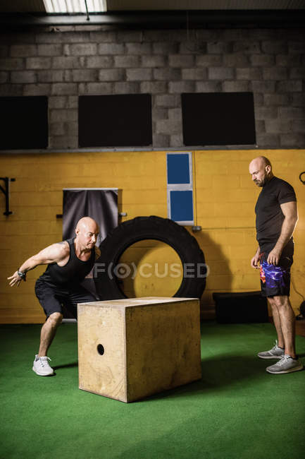 Два спортсмени, що працюють на дерев'яній коробці у фітнес-студії — стокове фото
