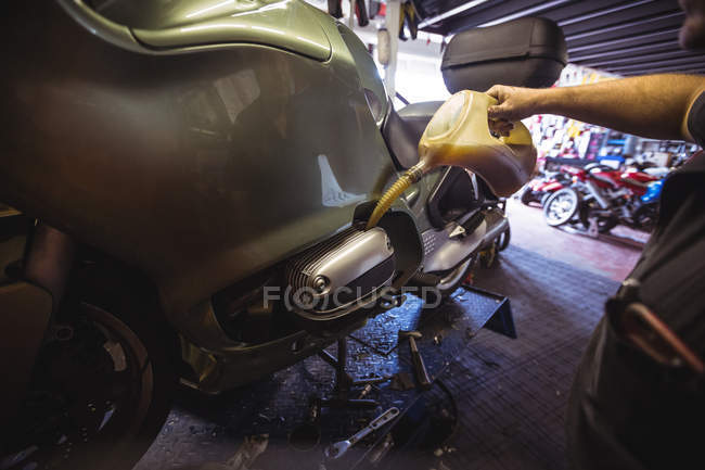Mechanic pouring oil into oil tank at workshop — Stock Photo