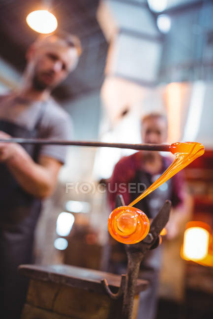Стеклодувы, формирующие расплавленное стекло на стекольном заводе — стоковое фото