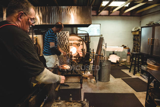 Glassblowers shaping molten glass at glassblowing factory — Stock Photo