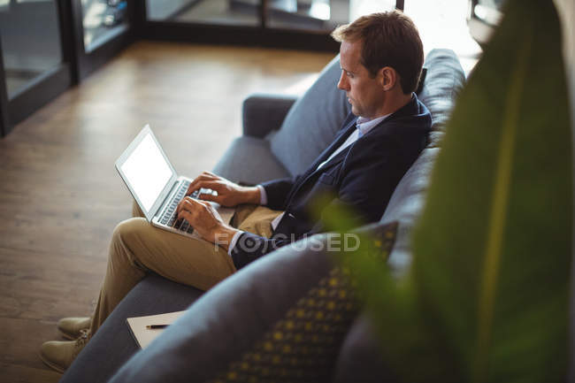 Businessman sitting on the sofa with laptop at office — Stock Photo