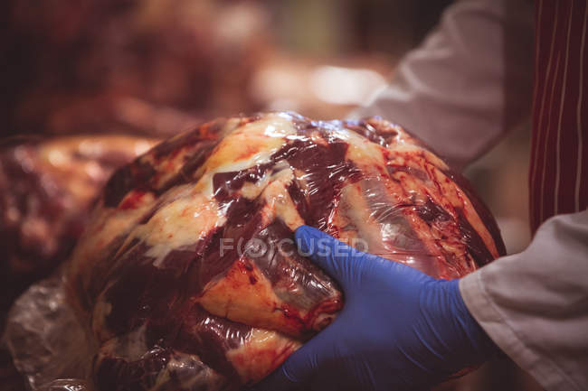Gros plan des bouchers tenant à la main de la viande rouge emballée — Photo de stock