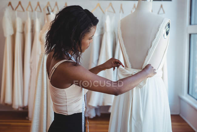 Créatrice de mode féminine ajustant la robe sur un mannequin en studio — Photo de stock