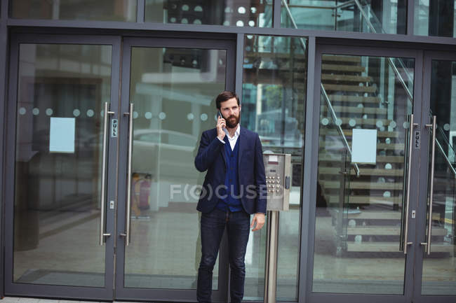 Uomo d'affari che parla al cellulare fuori dall'ufficio — Foto stock