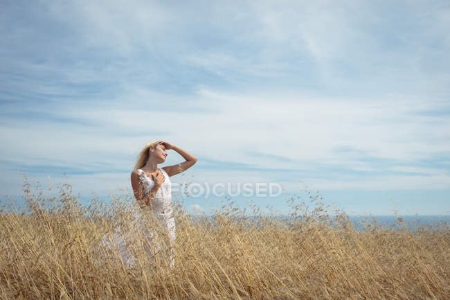 Femme blonde insouciante debout dans le champ — Photo de stock