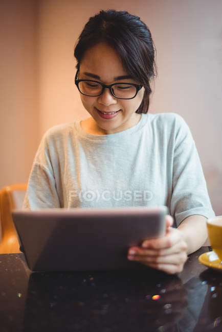 Jeune femme utilisant une tablette numérique au café — Photo de stock