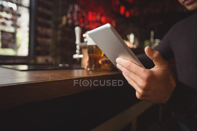 Partie médiane de l'homme utilisant tablette numérique dans le comptoir de bar au bar — Photo de stock