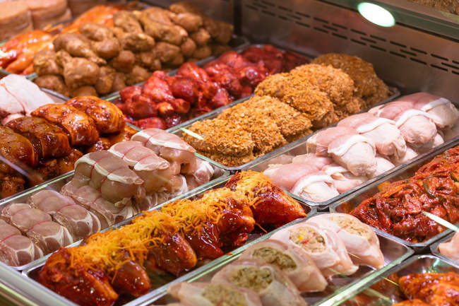 Variedade de carne marinada no balcão de exposição no açougue — Fotografia de Stock