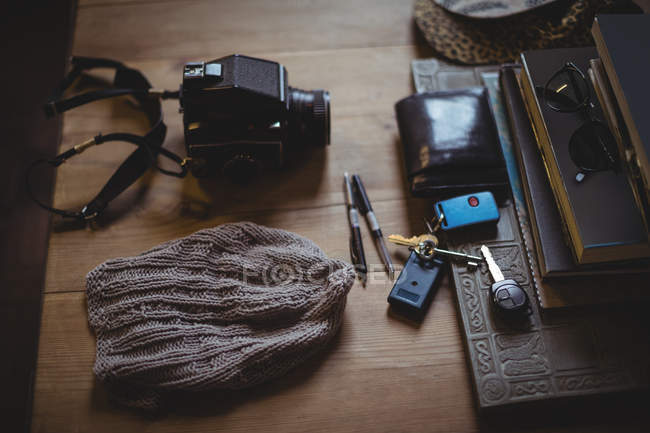 Вовняний капелюх, камера, ключ, гаманець, сонцезахисні окуляри, щоденник і ручки на столі — стокове фото