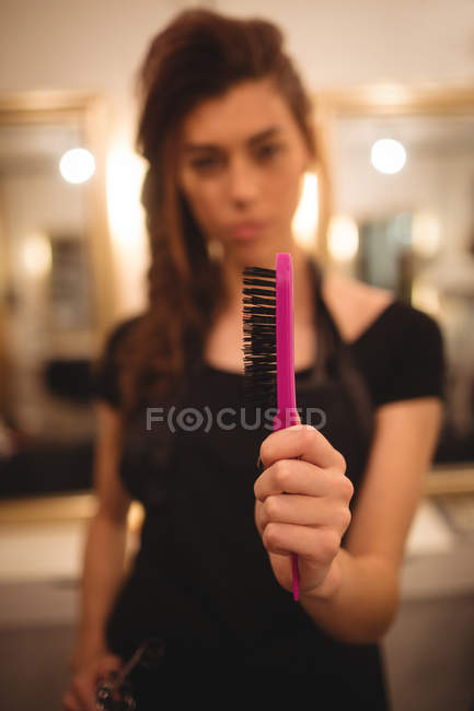 Femme coiffeuse tenant une brosse à cheveux au salon — Photo de stock