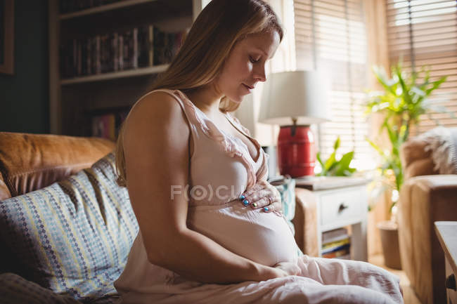 Vista lateral da mulher grávida relaxante na sala de estar em casa — Fotografia de Stock