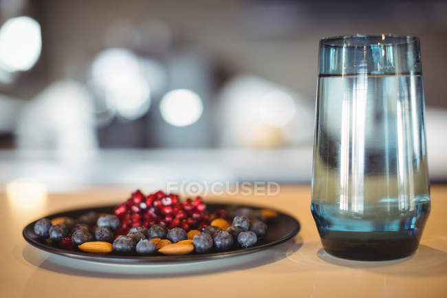Close-up de prato de lanches e vidro de água na mesa — Fotografia de Stock