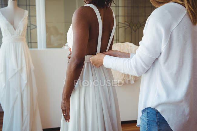 Жінка намагається на весільній сукні в студії за допомогою дизайнера моди — стокове фото