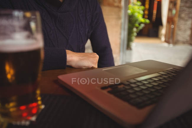 Mid section of man with laptop at bar — Stock Photo