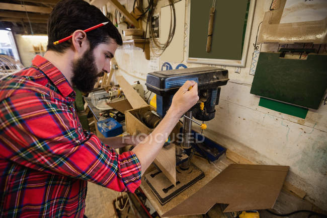 Uomo che fa un buco su tavola di legno in cantiere — Foto stock
