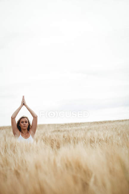 Frau mit erhobenen Händen in Gebetsposition auf Feld an sonnigem Tag — Stockfoto