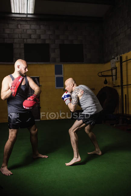 Vista lateral de dois boxers tailandeses atléticos praticando no ginásio — Fotografia de Stock