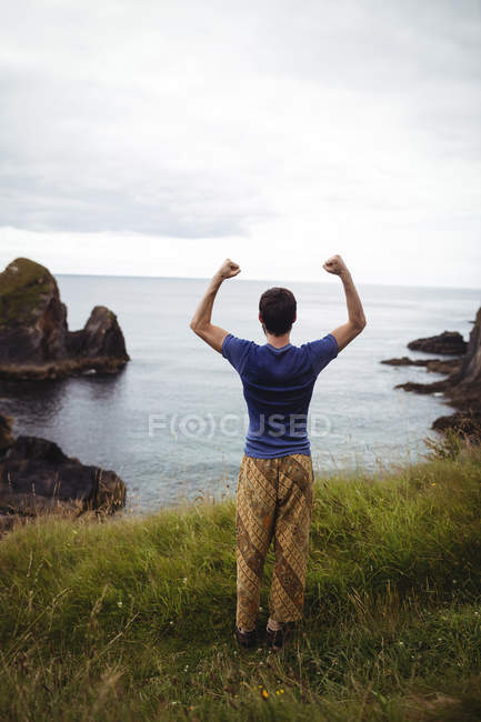 Rückansicht eines Mannes, der auf einer Klippe steht — Stockfoto