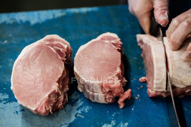 Mão de açougueiro cortando carne no açougue — Fotografia de Stock