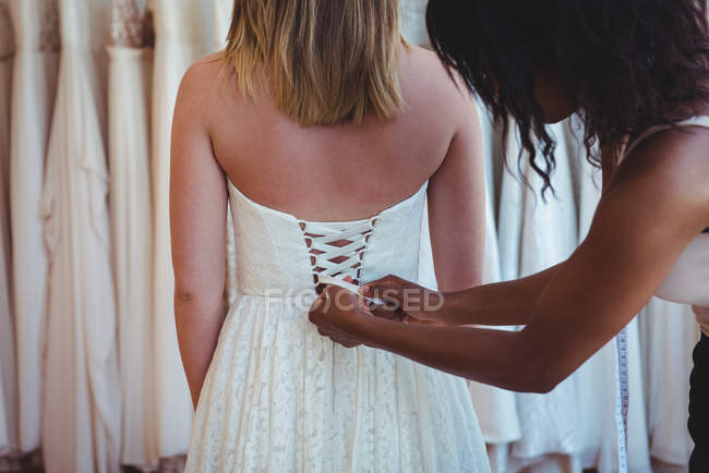 Donna che prova l'abito da sposa con l'assistenza dello stilista in studio — Foto stock