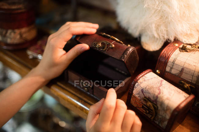 Primer plano de las manos abriendo un joyero de madera en una tienda de antigüedades - foto de stock