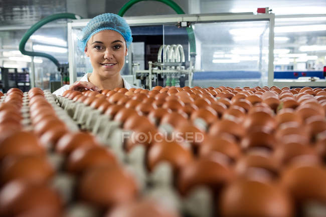 Portrait of female staff examining eggs in factory — Stock Photo