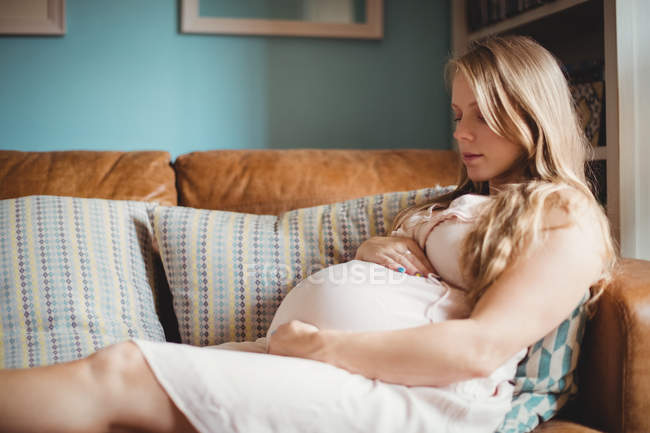Pregnant woman relaxing on sofa in living room at home — Stock Photo