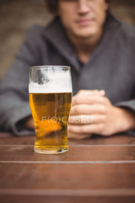 Mid section of man sitting in bar with glass of beer on table — Stock Photo