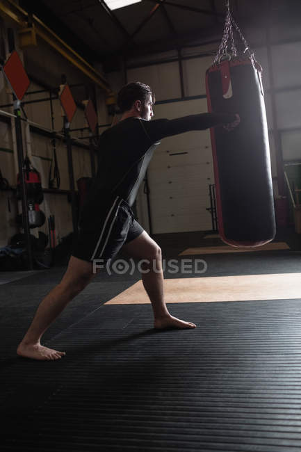 Низький кут зору боксер практикуючих бокс з боксерської груші в фітнес-студія — стокове фото