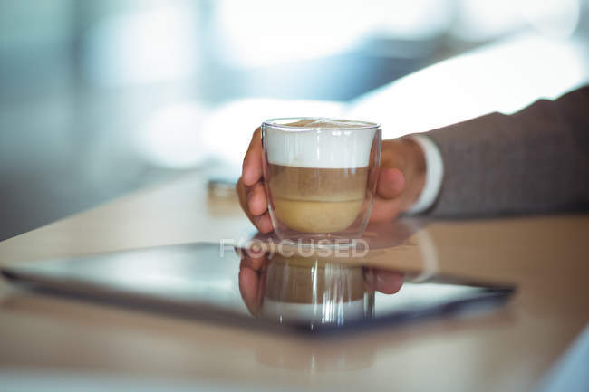 Primo piano dell'uomo d'affari che tiene in mano una tazza di caffè nel caffè — Foto stock