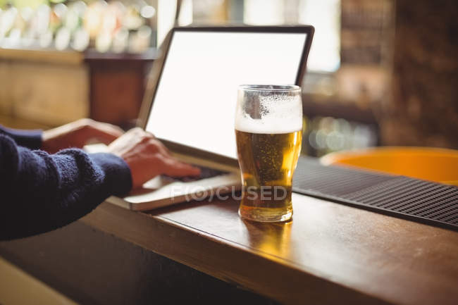 Gros plan de l'homme utilisant un ordinateur portable au comptoir du bar — Photo de stock