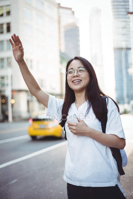Щаслива молода жінка закликає до таксі на вулиці — стокове фото