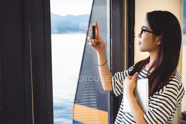 Hermosa mujer tomando fotos en el teléfono móvil de la nave - foto de stock