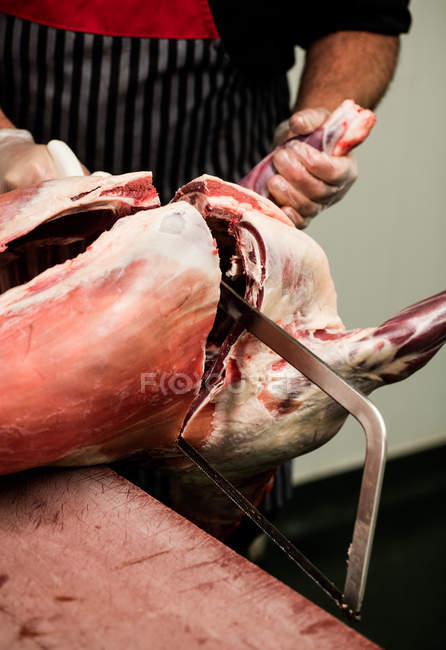 Seção intermediária do açougueiro cortando carcaça de porco com uma serra no talho — Fotografia de Stock